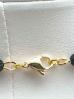 A MEN'S NECKLACE WITH LAVA STONE AND HOWLITE Gold plated bracelet with black lava and howlite beads.