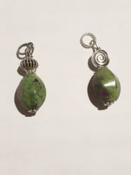 Two oval ruby zoisite pendants on a white surface.