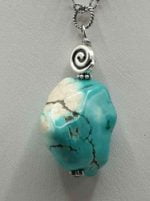 A TURQUOISE PENDANT on a silver chain.