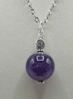 Un ciondolo pendente con ametista viola su catenina d'argento.