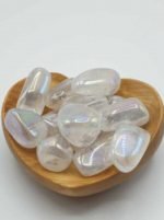 A wooden bowl filled with AURA ANGELI TUMBLED QUARTZ stones.