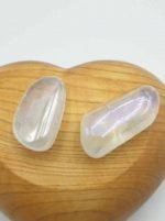 Two pieces of AURA ANGELI TUMBLED QUARTZ placed on top of a wooden heart.