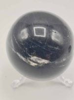 The BLACK TOURMALINE SPHERE on a white surface.