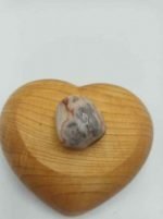 A stone in a heart-shaped box of TUMBLED CRAZY LACE AGATE.
