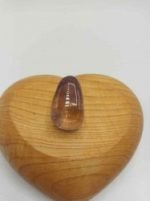 A TUMBLED AMETRINE stone in a heart-shaped wooden box.
