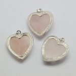 Three ROSE QUARTZ HEART PENDANT WITH PLATED BRASS BEZELS on white surface.