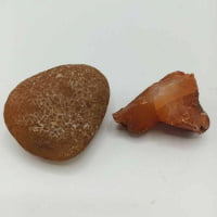 A piece of raw Red Carnelian and a piece of sand.