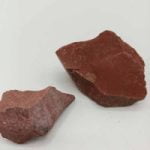 Two pieces of NATURAL RAW RED JASPER on a white surface.