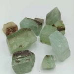 Un gruppo di pietre Calcite Verde Grezza Naturale su una superficie bianca.