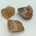 Three pieces of quartz CALCITE HONEY OR GOLDEN NATURAL RAW brown on white surface.