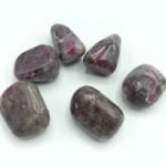 Group of stones RUBY BURLET FELDSPARE arranged in a tumbled pattern on a white background.