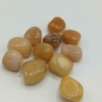 Group of yellow jade stones on a white background, embellished with TUMBLED RED AVENTURINE.
