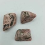 Three pieces pink Rhodochrosite Tumbled on a white surface.