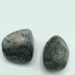 Pair of grey jade stones on TUMBLED TOURMALINATED QUARTZ surface.